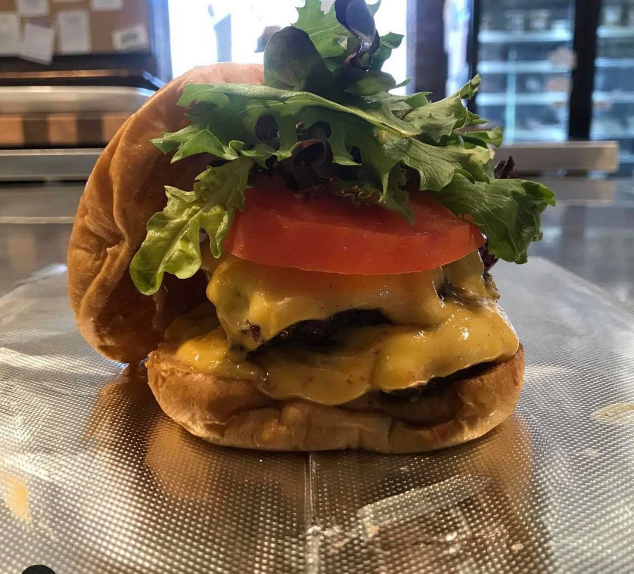 Double cheese burger with fresh tomato slice and lettuce on a roll